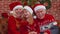 Senior grandparents with granddaughter in Santa hats laughing out loud at home near Christmas tree
