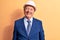 Senior grey-haired architect man wearing suit and security hardhat over yellow background with a happy and cool smile on face