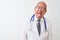 Senior grey-haired doctor man wearing stethoscope standing over isolated white background sticking tongue out happy with funny