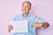 Senior grey-haired man holding blank empty banner smiling looking to the side and staring away thinking