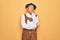 Senior grey-haired man wearing german traditional octoberfest suit over yellow background with hand on chin thinking about