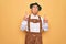 Senior grey-haired man wearing german traditional octoberfest suit over yellow background Pointing up looking sad and upset,