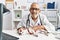 Senior grey-haired man wearing veterinarian uniform examining chihuahua at vet clinic