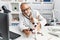 Senior grey-haired man wearing veterinarian uniform examining chihuahua at vet clinic