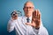 Senior grey haired optic doctor man holding optometrist eyeglasses over blue background with open hand doing stop sign with