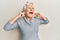 Senior grey-haired woman covering ears with finger angry and mad screaming frustrated and furious, shouting with anger looking up