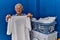 Senior grey-haired woman smiling confident holding white t shirt at laundry room