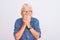 Senior grey-haired woman wearing denim shirt and glasses over isolated white background laughing and embarrassed giggle covering