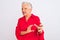 Senior grey-haired woman wearing red casual shirt standing over isolated white background disgusted expression, displeased and