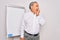 Senior handsome grey-haired businessman doing presentation using magnetic board looking stressed and nervous with hands on mouth