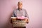 Senior handsome hoary man doing housework holding wicker basket with clothes with a confident expression on smart face thinking