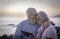 Senior happy couple having fun looking at the same tablet sitting at dusk on the beach. Retired people enjoying technology,