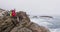 Senior hiker man with backpack sitting on the rocks while hiking near sea shore.