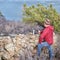 senior hiker at old stone fence overlooking frozen mountain lake