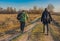 Senior hikers with backpacks walking on a country road