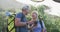 Senior hiking couple with bag packs using digital camera in the woods while hiking in the mountains.