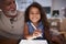 Senior Hispanic man with his young granddaughter using stylus and tablet computer, smiling to camera