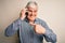 Senior hoary man having conversation talking on the smartphone over white background very happy pointing with hand and finger