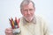 Senior holding a mug of pens and pencils.