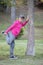 Senior Japanese man wearing pink parka doing calf stretch by tree