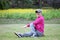 Senior Japanese man wearing pink parka doing seated torso twist stretch on a lawn