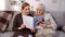 Senior ladies reading modern magazine sitting sofa, nursing home leisure, rest
