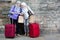 Senior ladies with suitcases and map near stone wall