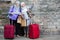 Senior ladies with suitcases and map near stone wall