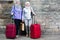 Senior ladies with travelling bags near stone wall