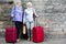 Senior ladies with travelling bags near stone wall