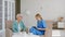 Senior lady patient with glasses talks to attentive young nurse writing on clipboard in living room