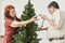 Senior Latino couple decorating a Christmas tree, putting a string of lights