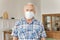 Senior male in facial medical mask staying at home