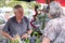 Senior male grower at farmers market smiling and showing organic