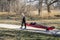 Senior male kayaker in a wetsuit is transporting his sea kayak on a cart for early spring paddling