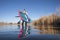 senior male paddler is launching a stand up paddleboard on a calm lake