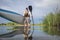 senior male paddler is launching a stand up paddleboard on a calm lake in spring