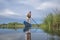 senior male paddler is paddling a stand up paddleboard on a calm lake in spring