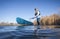 senior male paddler is rinsing his stand up paddleboard after paddling on a calm lake