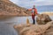 senior male paddler with a wooden canoe paddle on a rocky shore of a mountain lake