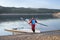 Senior male rower with a coastal rowing shell and hatchet oars on a shore of Carter Lake