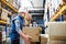 Senior male warehouse worker unloading boxes from a pallet truck.