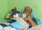 Senior man asleep in bed with soft cuddly toys.