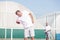 Senior man with backache while standing against friend during tennis match on sunny day