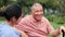 Senior man, caregiver and conversation in outdoors, rehabilitation and humor in consultation. Park bench, nurse and