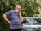 Senior man on cell phone in road next to car calls