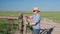 Senior man in a cowboy hat, farmer or rancher, is opening cattle gate