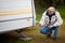 Senior Man Crouching While Repairing Caravan