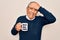 Senior man drinking cup of coffee with best dad ever message over white background stressed with hand on head, shocked with shame