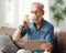 Senior man drinking hot beverage and using tablet